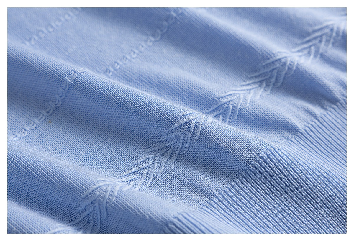 Macro view of light blue knit texture with raised zigzag seam details and ribbed trim.