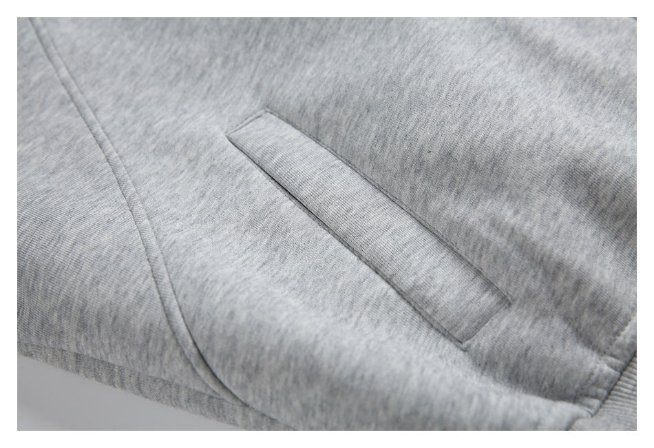 Close-up of a slanted welt pocket on gray heather fabric, with curved seam detailing.