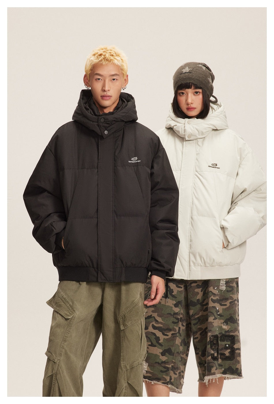 Two models wear hooded padded jackets, one black and one white, against a neutral studio background.