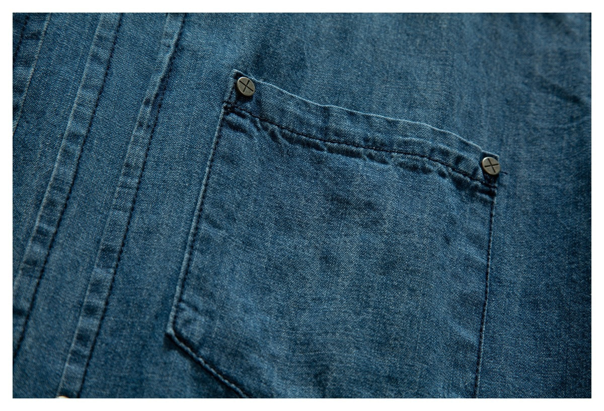 Close-up of a blue denim garment's patch pocket with two dark metal buttons.