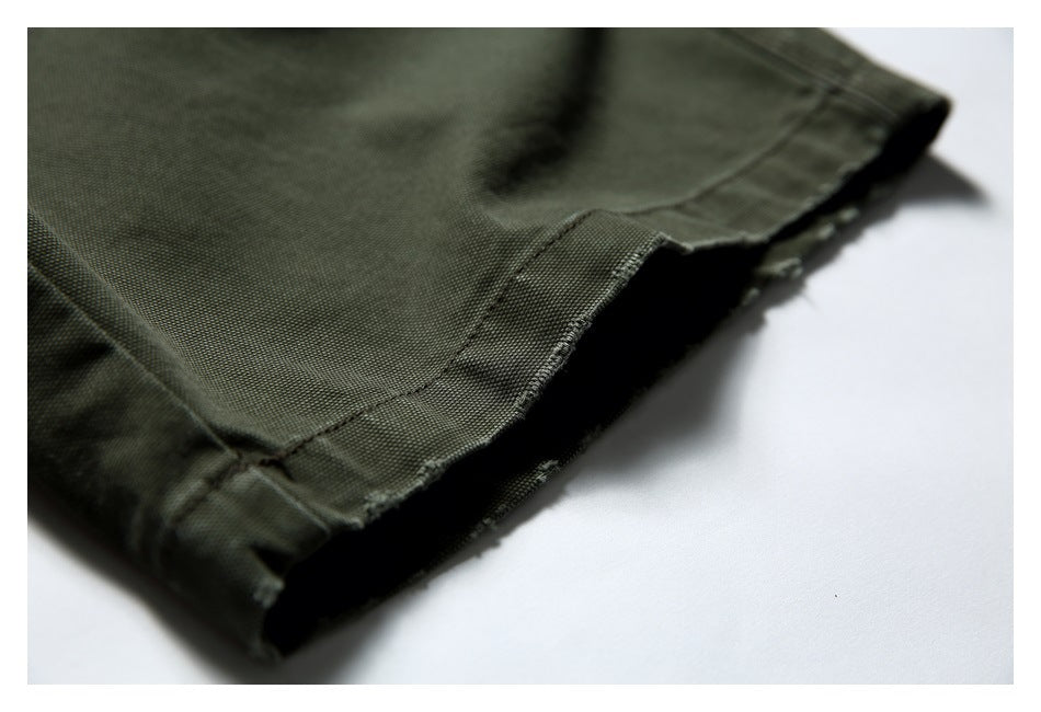 Close-up of olive trousers showing a double-stitched folded hem and textured fabric.