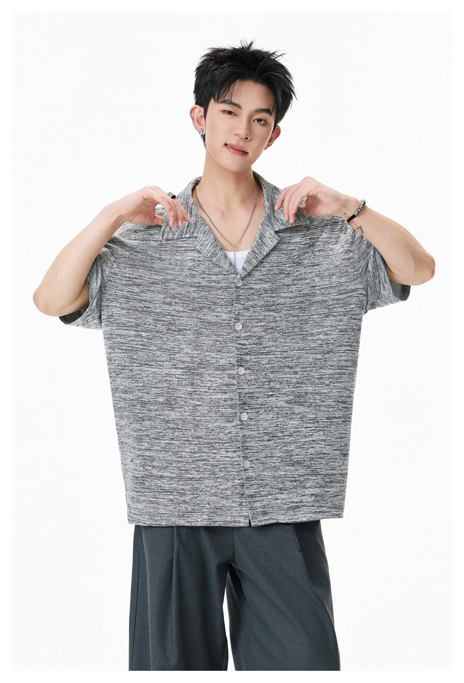 Closer view of a model holding out the front of a gray marled short-sleeve button-front shirt.
