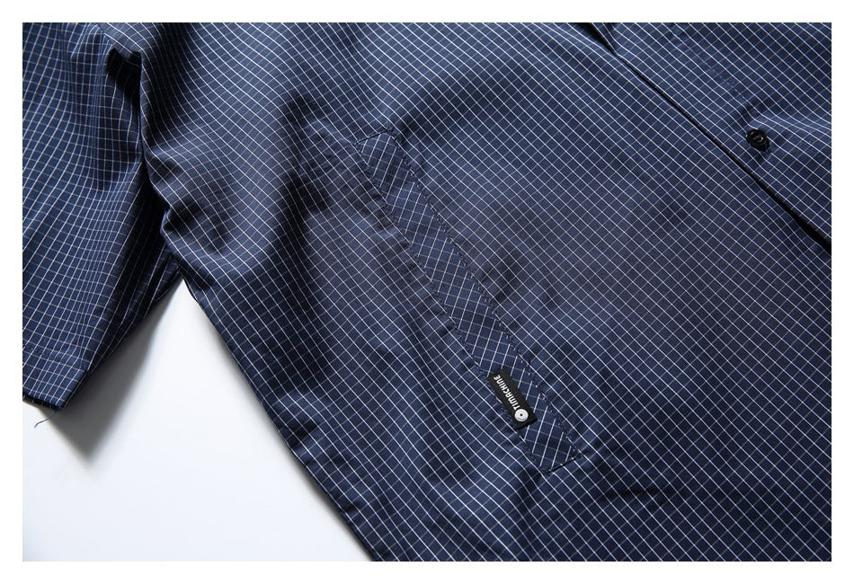 Close-up of a navy check shirt showing its chest pocket and button placket.