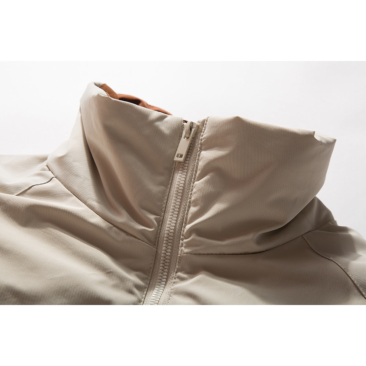 Close-up of a beige jacket's tall collar and central zipper.