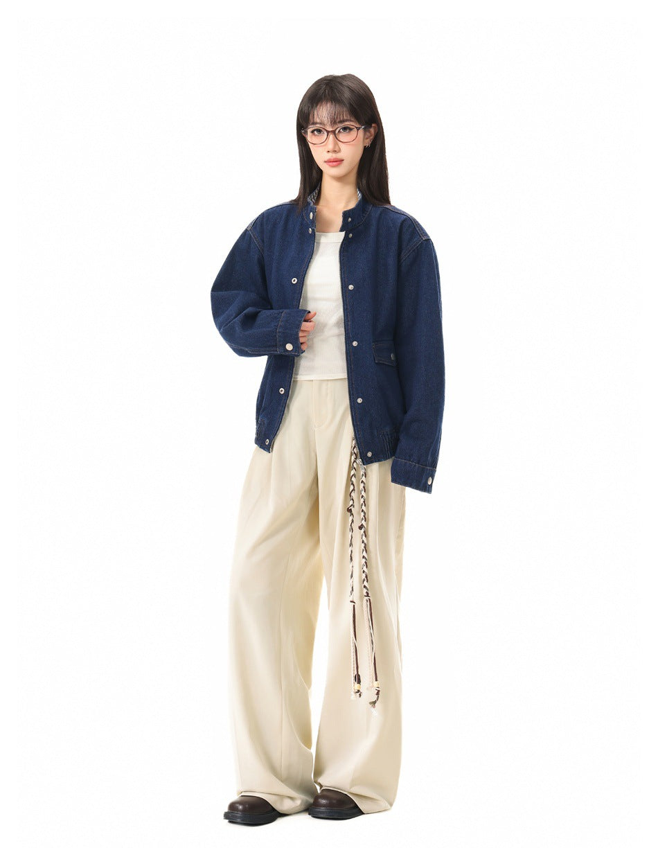 Full-length model wearing a dark blue denim jacket over a white top and cream wide-leg trousers.