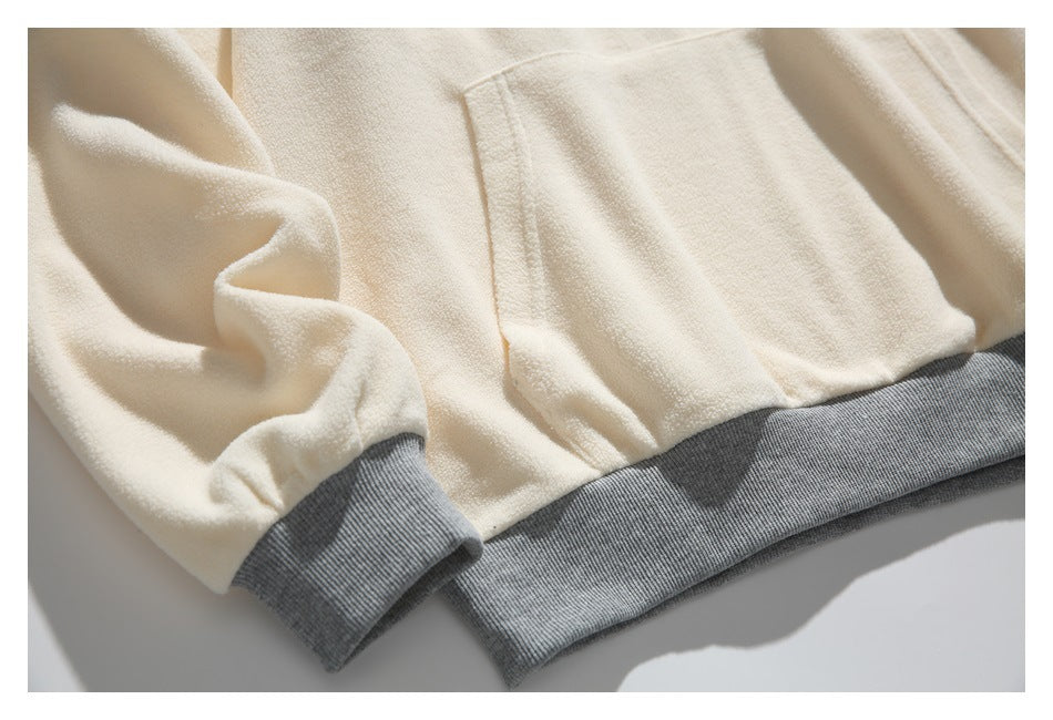Close-up of a cream fleece pullover with gray ribbed hem and cuff.