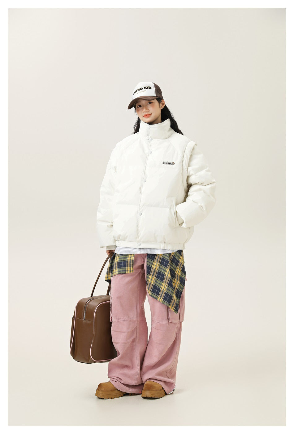 Model wearing an ivory snap-front puffer jacket with a high collar and side pockets, shown from the front.