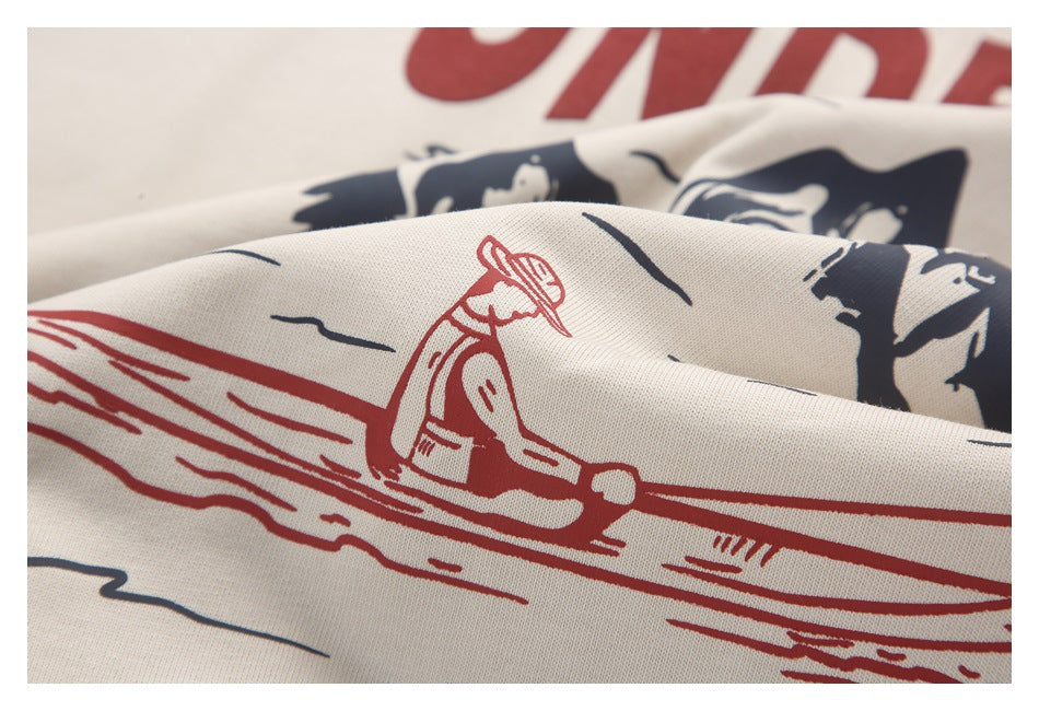 Close-up of a beige shirt's red and navy outdoor illustration, including a person in a canoe.