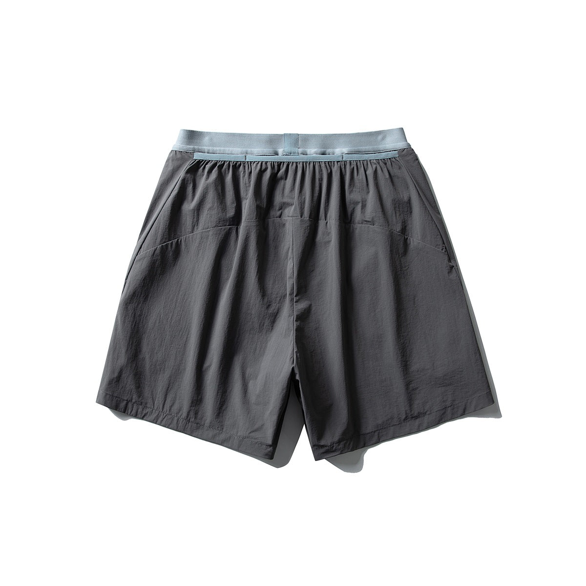 Back view of loose charcoal shorts with a pale blue waistband and wide legs, laid flat on white.