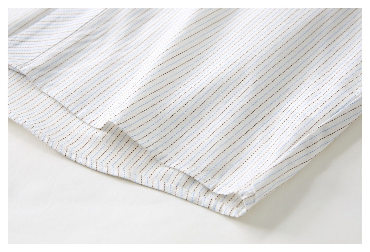 Close-up of a white shirt’s striped lower hem and stitched seam.