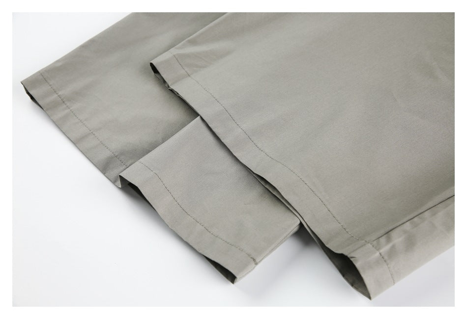 Close-up of the straight hems on taupe-gray trouser legs.
