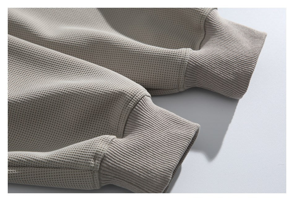 Close-up of two ribbed cuffs on a taupe waffle-knit garment.