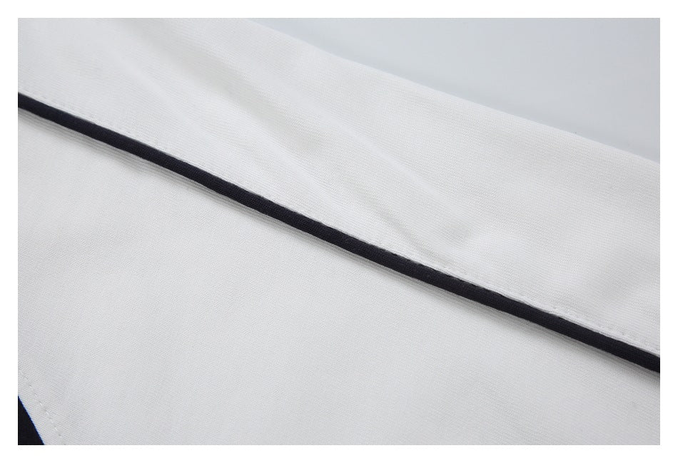Close-up of a narrow black piping detail running along white garment fabric.