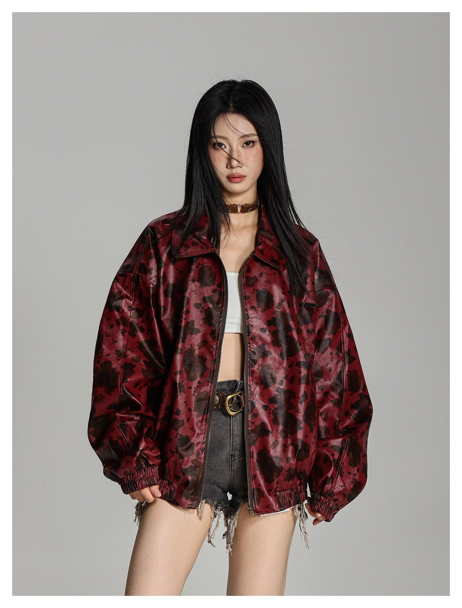 Model in a burgundy mottled zip jacket with a pointed collar and voluminous sleeves, shown from the front.