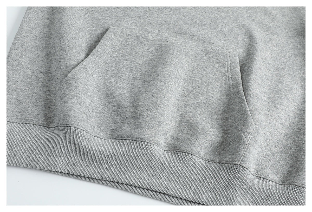 Close-up of the gray sweatshirt's front kangaroo pocket openings and ribbed hem.
