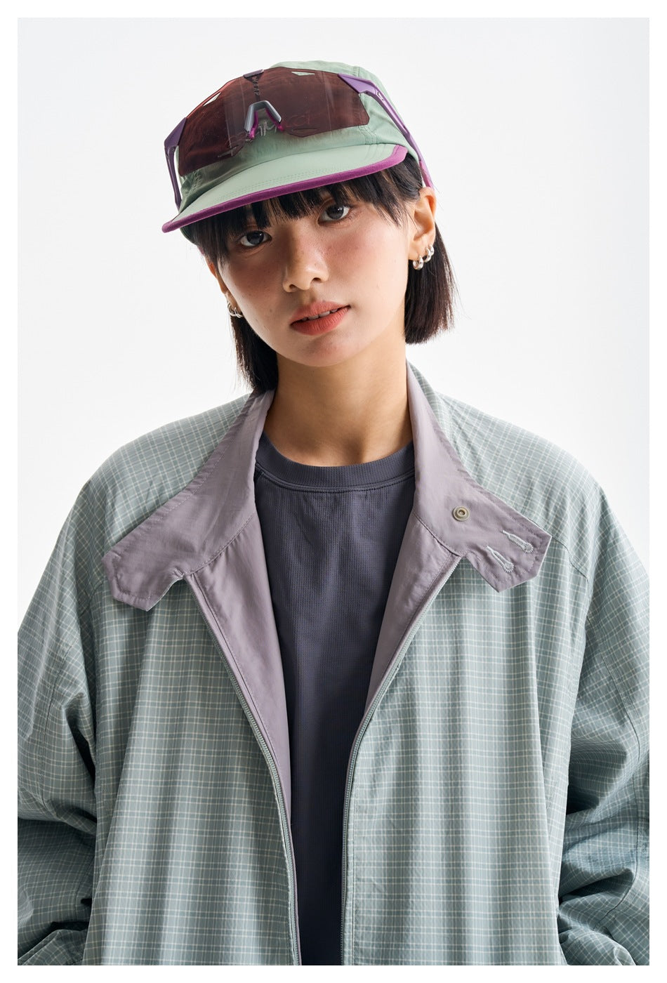 Close-up of a model wearing a sage green plaid jacket with pale lavender trim.