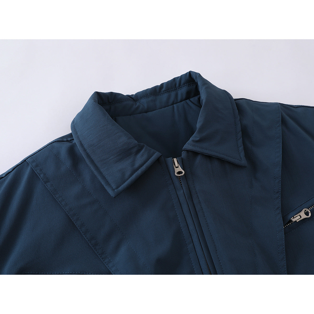 Close-up of a dark navy jacket collar, central zipper, stitched panels, and a partially visible zip pocket.