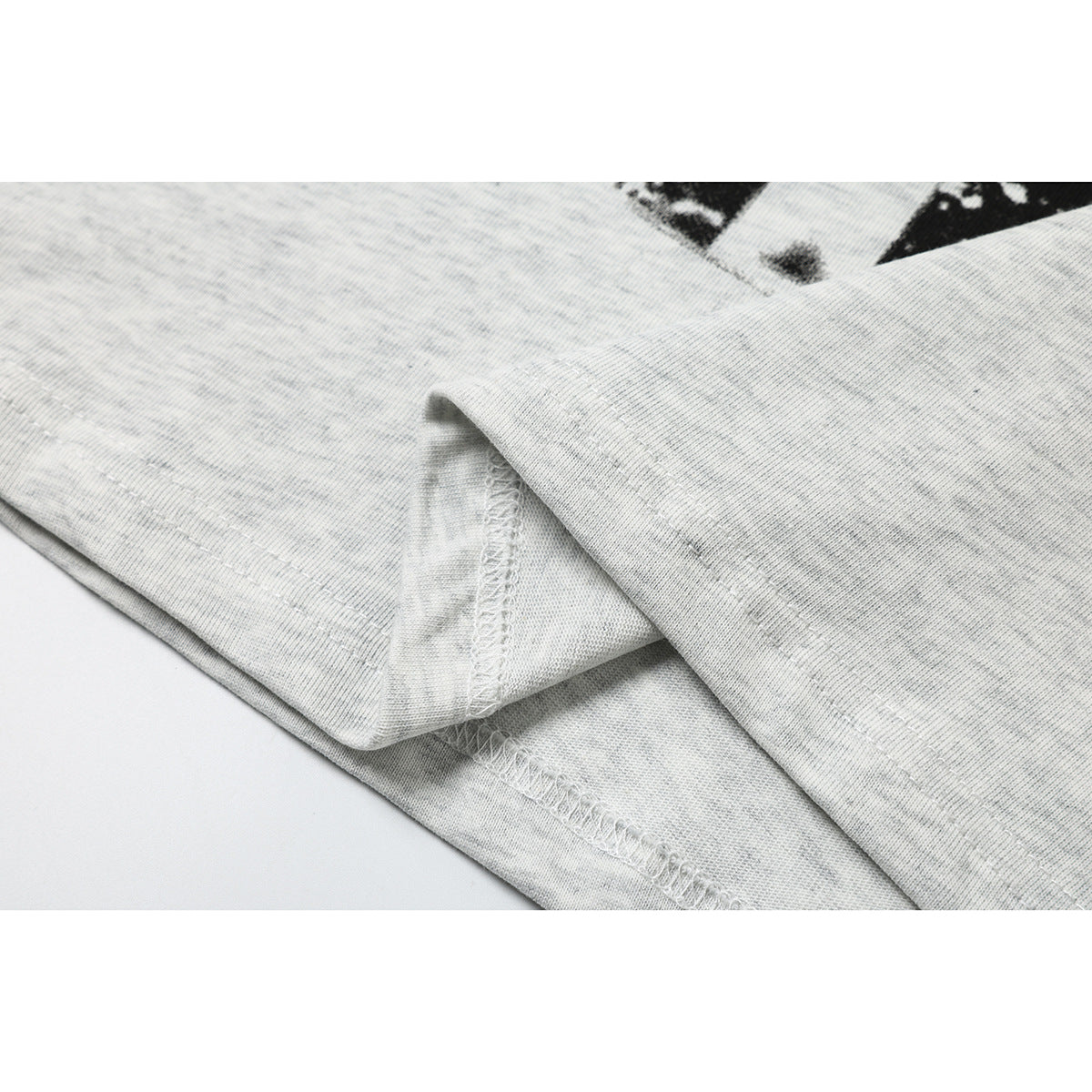 Close-up of the light gray T-shirt's folded hem and overlock stitching, with a small part of its print visible.