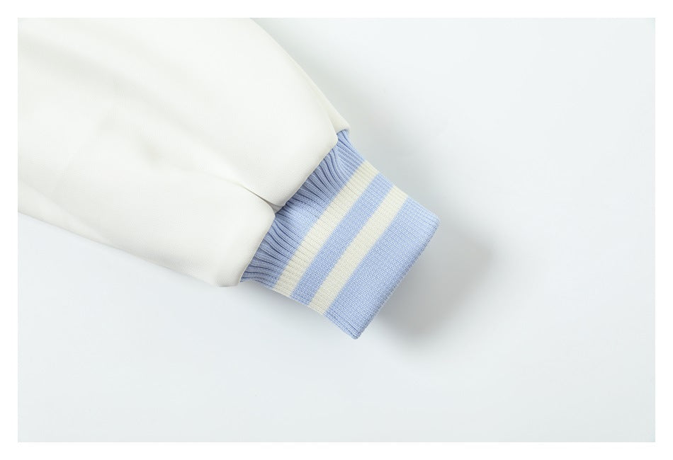 Close-up of a white sleeve ending in a pale blue and cream striped rib-knit cuff.