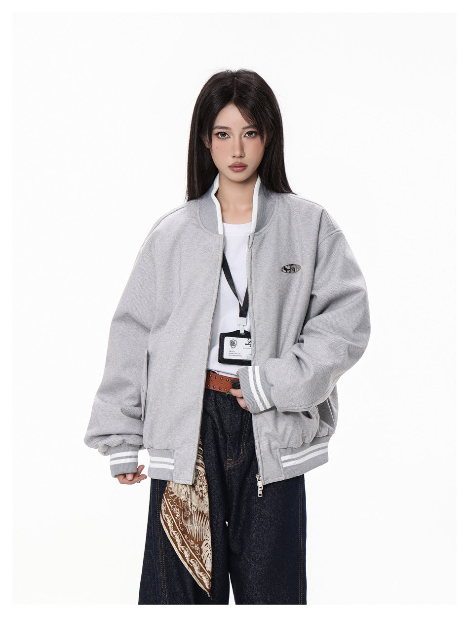 Model wearing an open light gray oversized bomber jacket with striped cuffs and hem, front pockets, and a small chest emblem.
