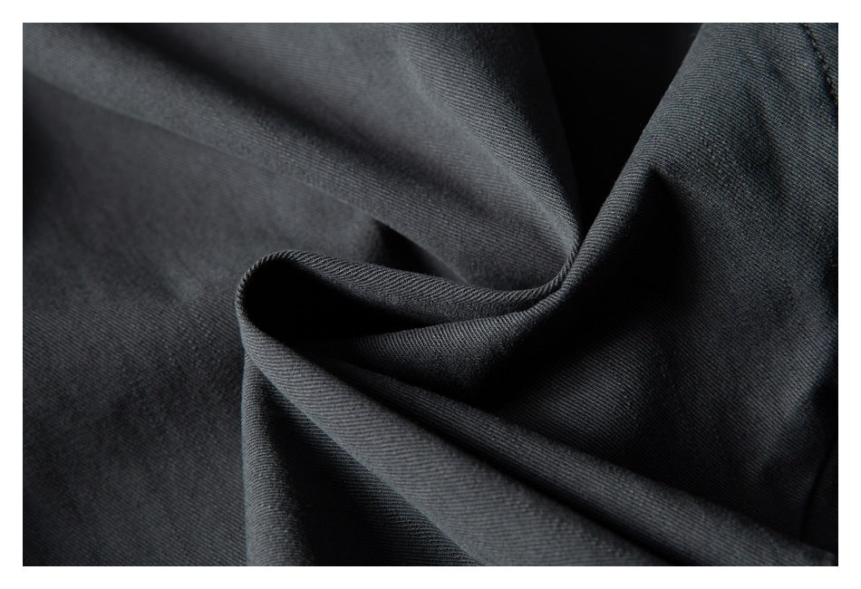 Close-up of dark charcoal fabric folded to show its fine diagonal weave and texture.