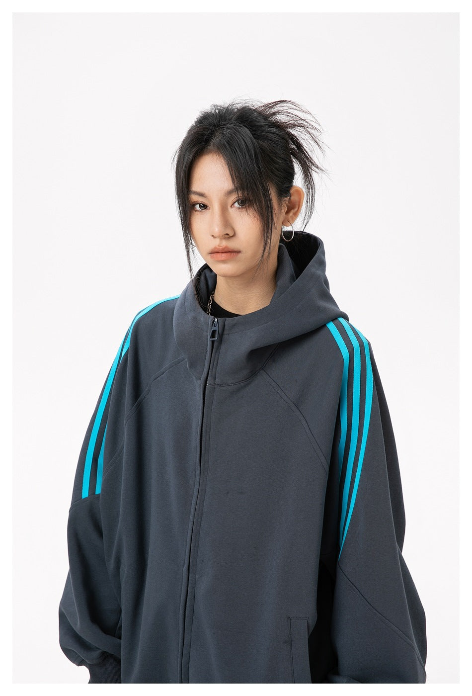 Close view of a model wearing a charcoal zip-up hoodie with bright cyan stripes along the sleeves.
