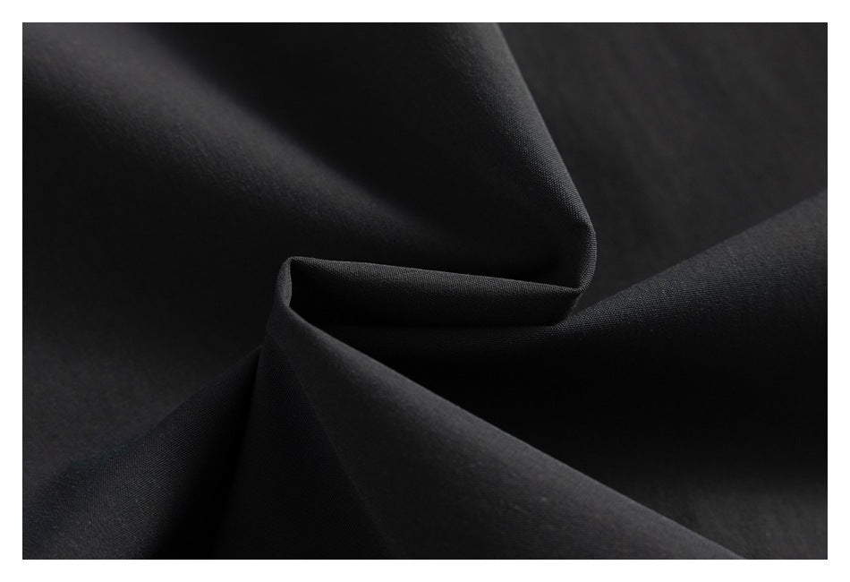 Close-up of black fabric arranged in soft folds, showing its fine woven texture.