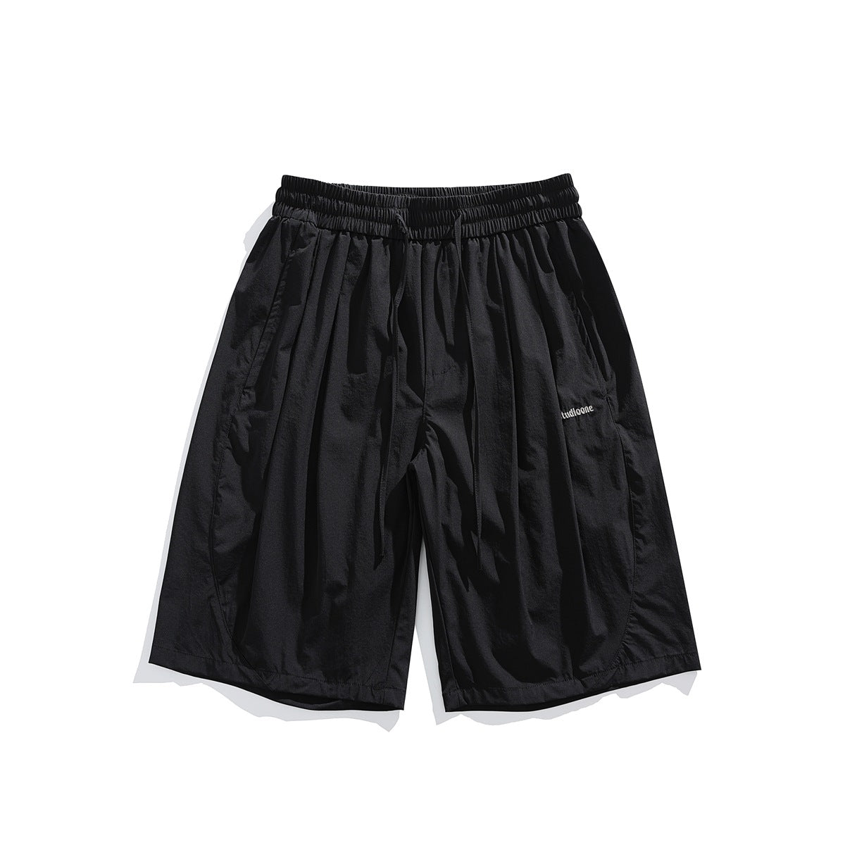 Front view of black loose-fit shorts with an elastic drawstring waist and small embroidered lettering.