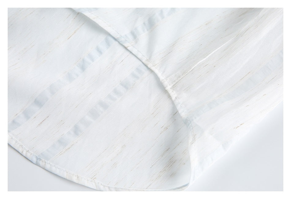 Close-up of a curved shirt edge and overlapping stitched seams on white fabric with subtle tan and pale blue accents.