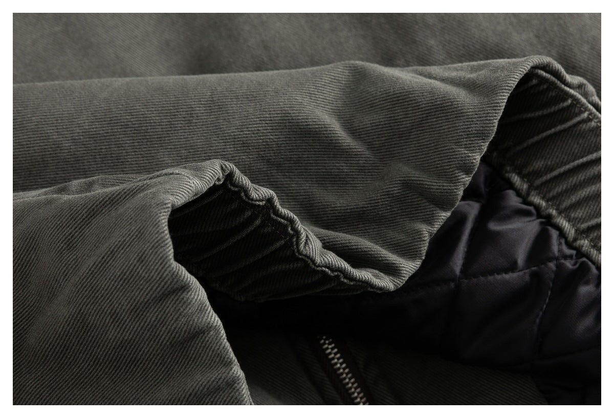 Close-up inside the jacket showing olive-gray fabric, black quilted lining, and part of a zipper.