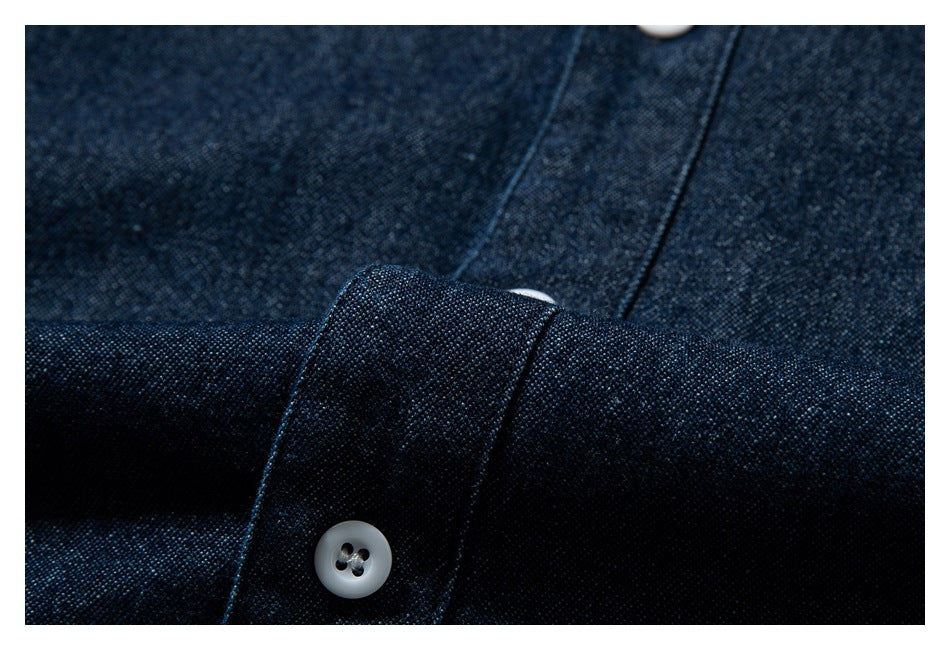 Close-up of dark indigo fabric, a white button, and a folded button band.