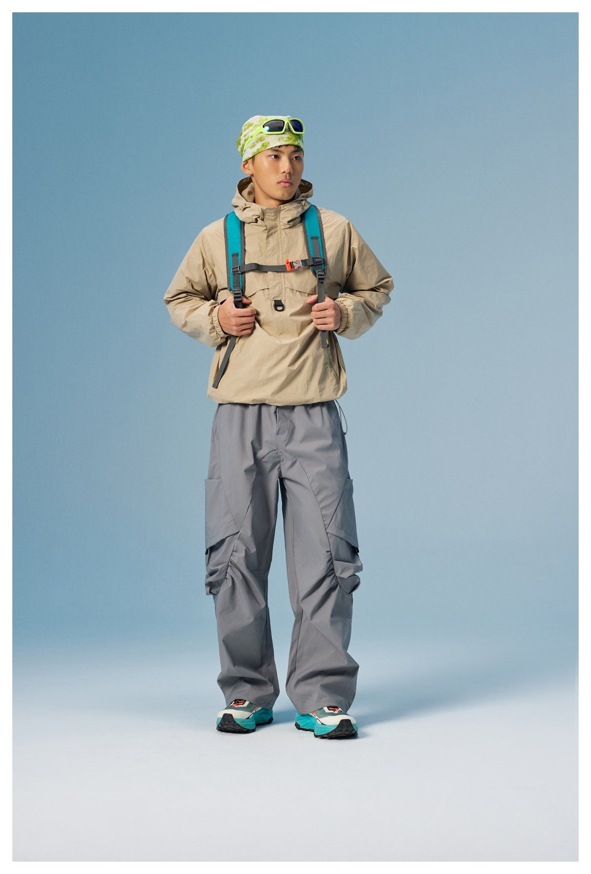 Front view of a model wearing a beige hooded pullover and loose gray cargo pants.