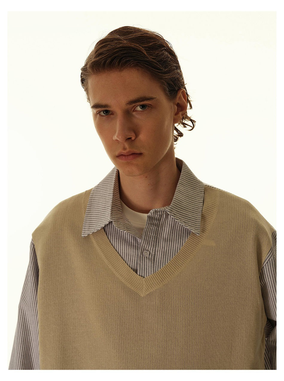 Close view of a model wearing a tan V-neck sweater vest over a gray striped collared shirt.