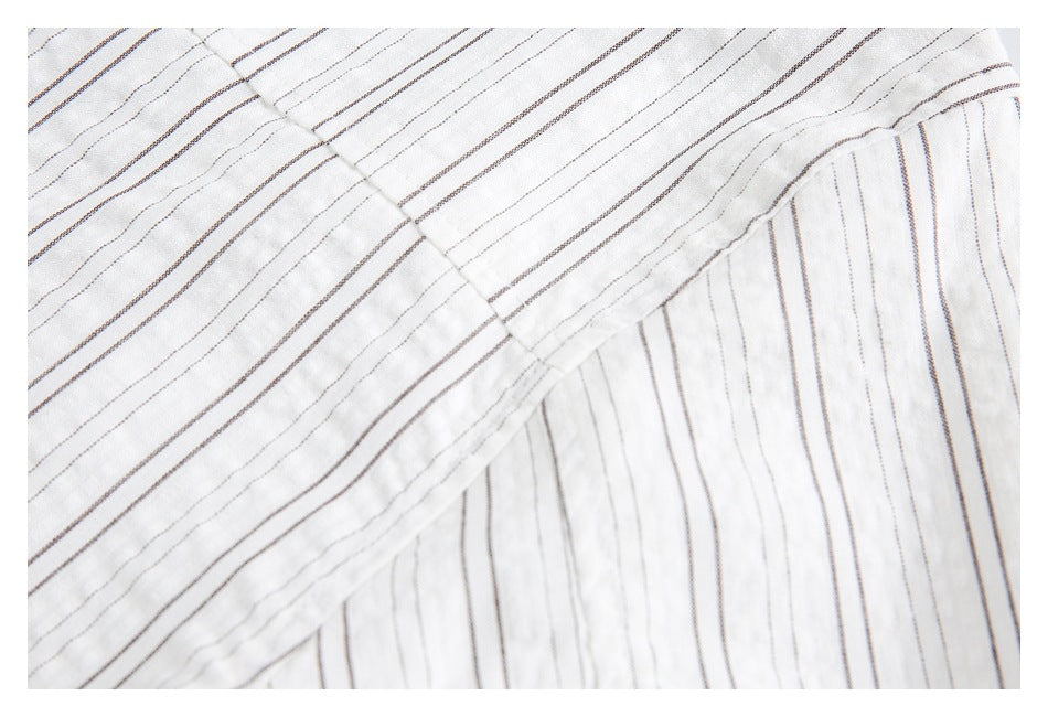 Close-up of a gathered seam joining white fabric panels with fine dark stripes.