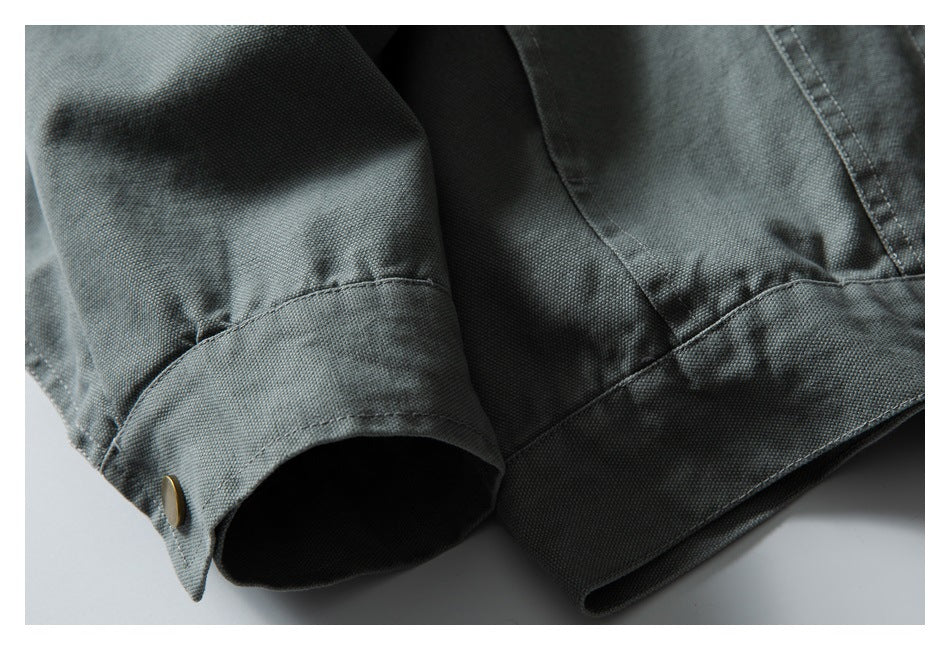 Close-up of the gray-green jacket's sleeve cuff and lower hem, with a brass-colored cuff button.