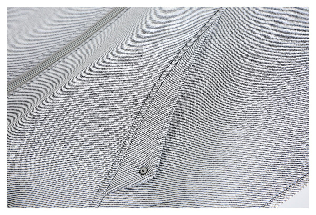 Close-up of the striped jacket front with zipper, panel seams, and a small snap-fastened flap.