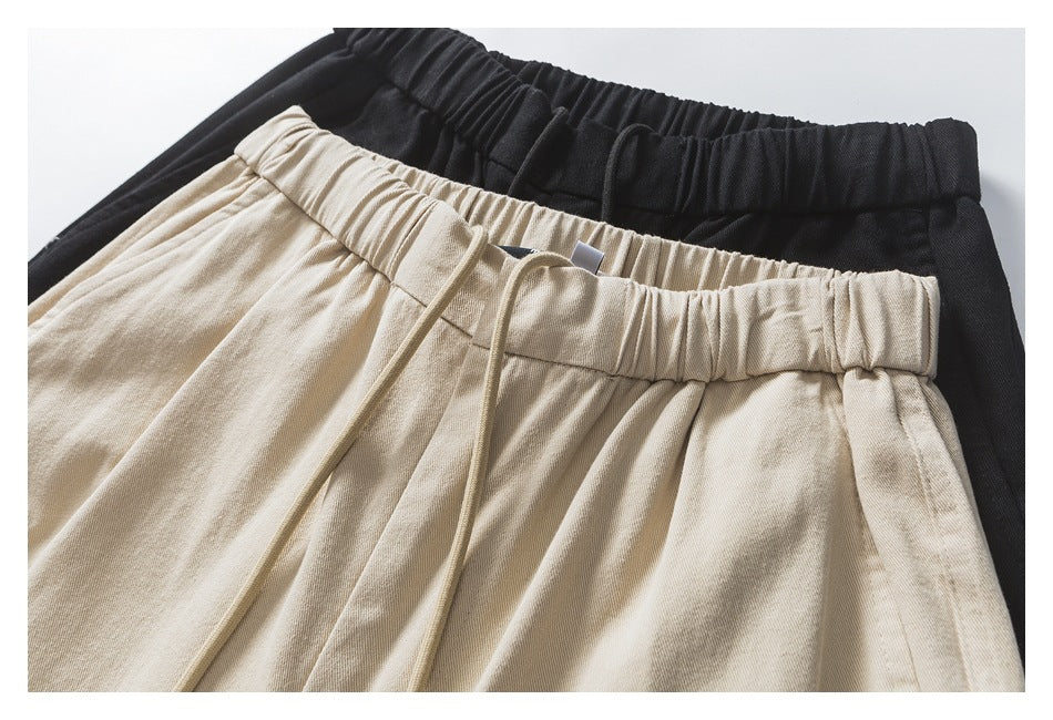Close-up of beige and black pants waistbands, with an elastic waist and drawstring on the beige pair.