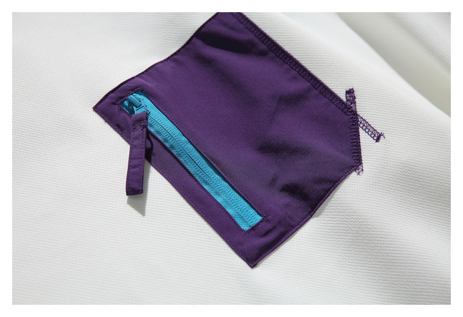 Close-up of a purple sweatshirt pocket with a bright turquoise zipper on white fabric.