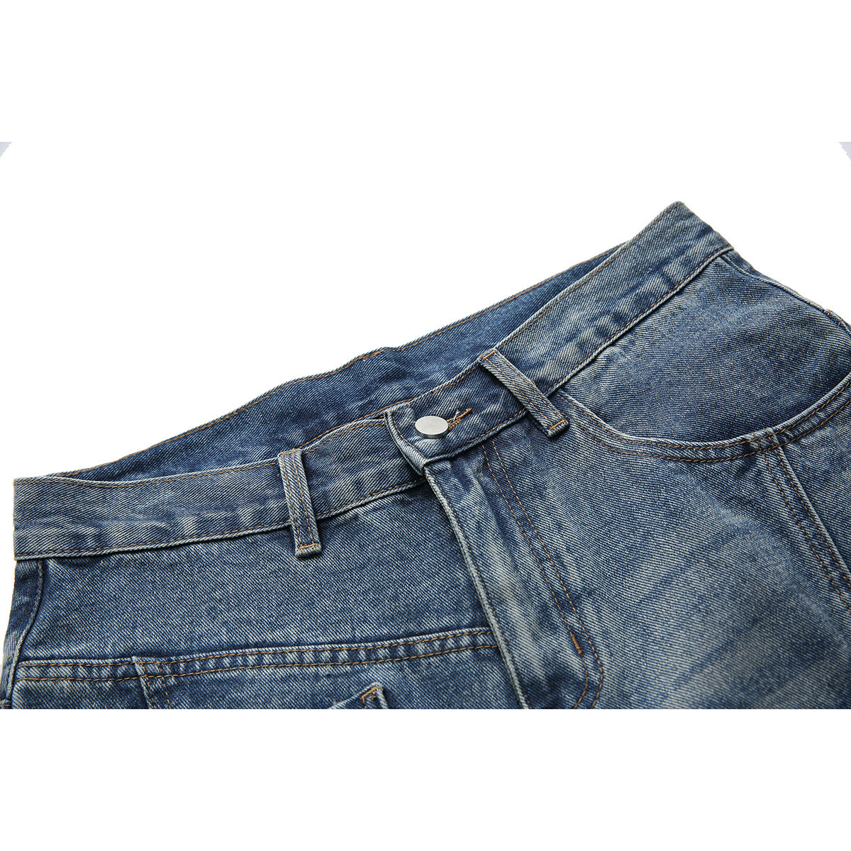Close-up of blue washed jeans showing the waistband, belt loops, silver button, fly stitching, and front pocket.