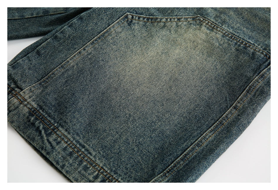 Close-up of a large stitched pocket on faded blue denim jeans.