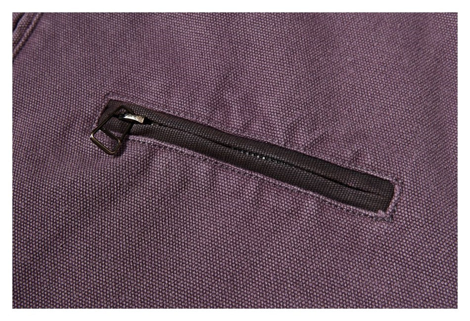 Close-up of a horizontal zip pocket on plum-colored textured jacket fabric.