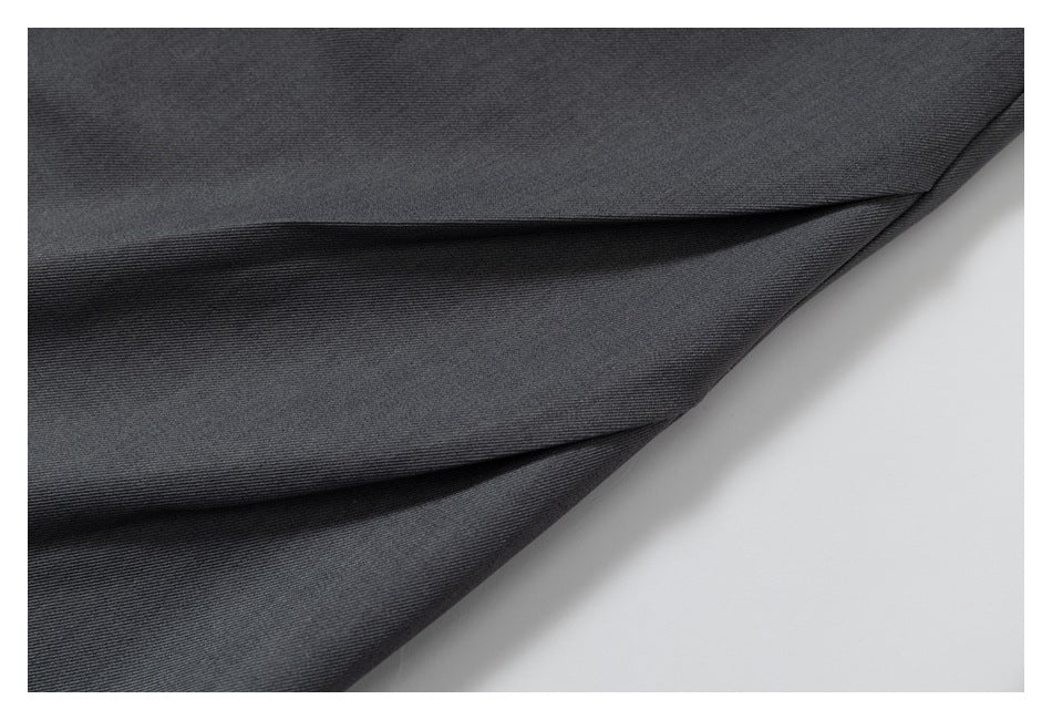 Close-up of dark charcoal trouser fabric arranged in soft folds.