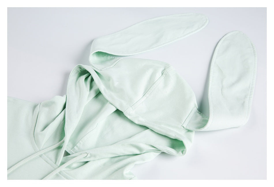 Close-up of the pale mint hood and its long floppy bunny ears, with part of the drawstring neckline visible.