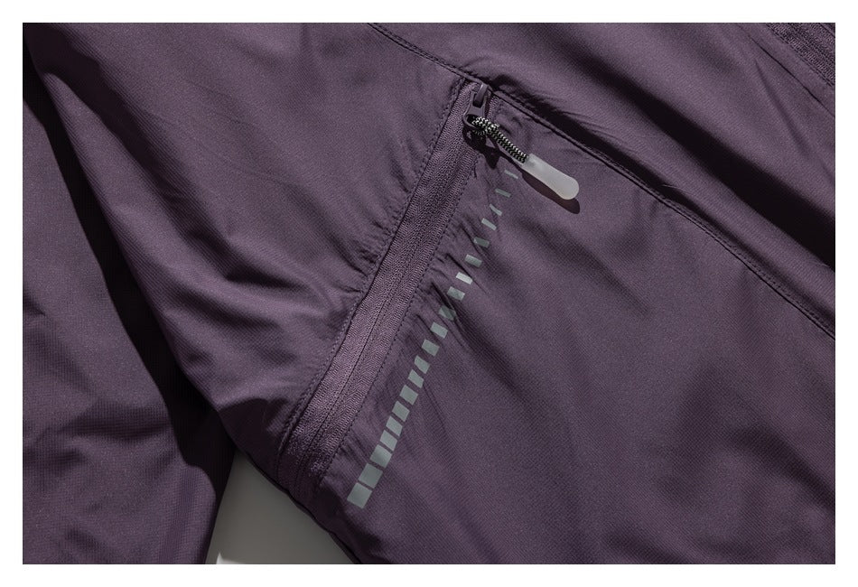 Dark plum garment detail showing a zippered seam and a row of reflective rectangular marks.