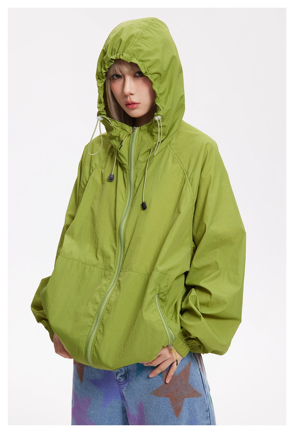 Model wearing a zipped lime-green hooded jacket with an adjustable hood and front zip pockets.