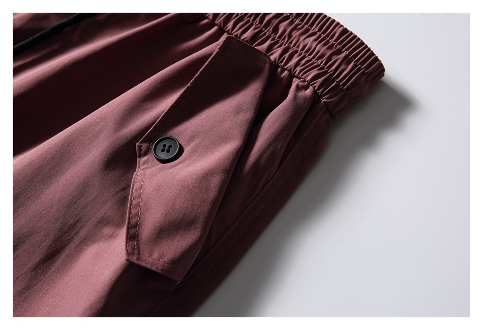 Close-up of dusty mauve trousers showing the elastic waistband and a buttoned flap detail.
