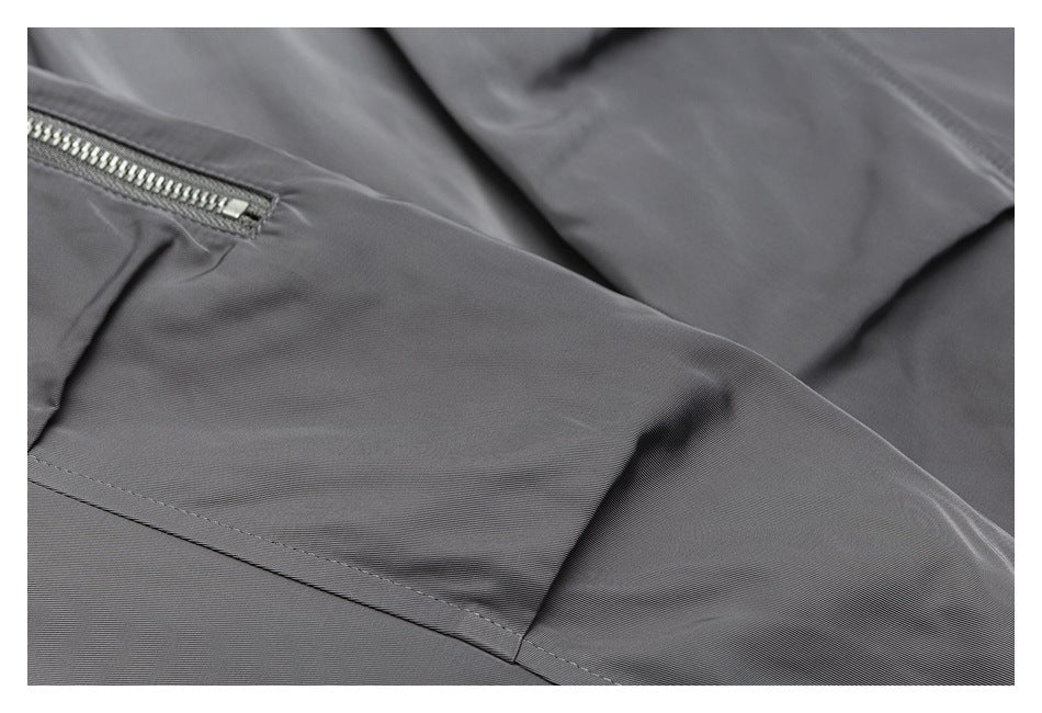 Close-up of gray garment fabric with a small silver zippered pocket and stitched seams.
