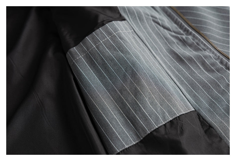 Close-up of a charcoal pinstripe garment showing a striped panel beside dark lining and a zipper edge.