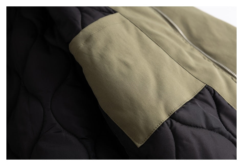 Close-up of an olive jacket panel and seam against dark quilted lining.