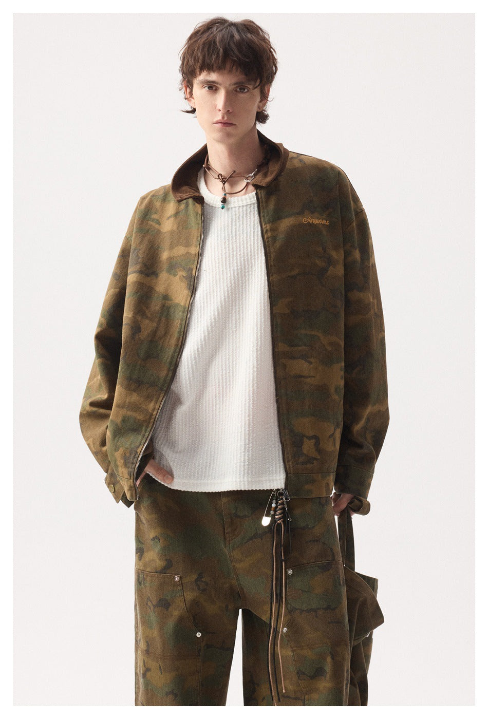 Model wearing open camouflage jacket with brown collar over white textured top and matching camouflage pants